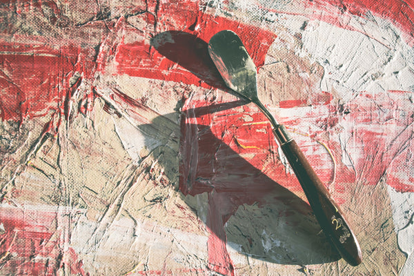 A photo showing a black handle spoon on a red and white painting