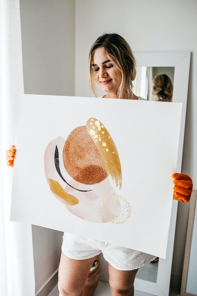 A woman holding a white and brown painting
