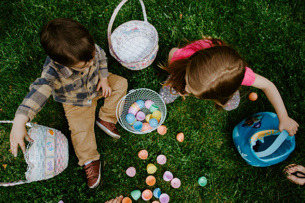 Kids sitting on grass with Easter eggs in their baskets