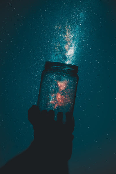 A person holding a jar against the dark night