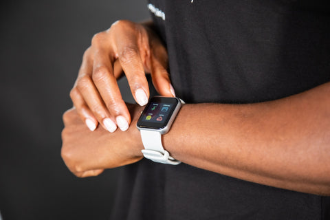 A female wearing a workout t-shirt and tracking her fitness goals on her fitness watch.