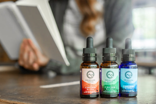 cbd dropper bottles with a woman reading at the back