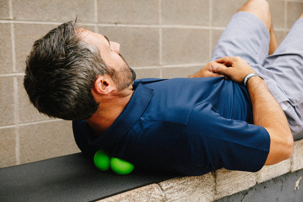 man in blue lying on two green balls