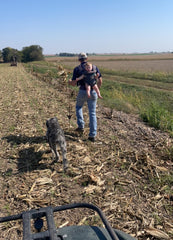 Man walking through cornfield with baby daughter in carrier