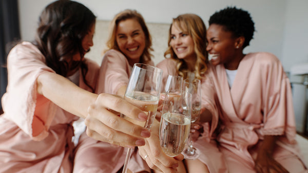 4 women in pink satin roses cheering with champagne celebrating an engagement