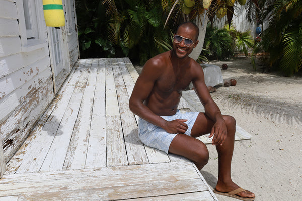 smiling african american man relaxes on steps on a tropical beach