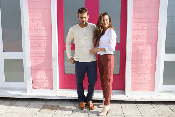 man and woman stand in front of a bright pink doorway