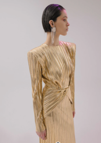  Model wearing a gold designer luxury women’s dress.