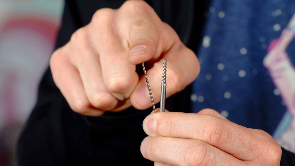 Hand holding drill bits and pointing to them