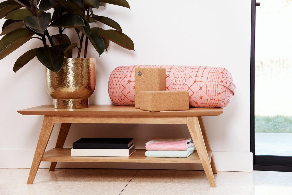 Manduka Enlight Round Bolster & Cork Blocks sitting on a side table in home yoga space | Eco Yoga Store