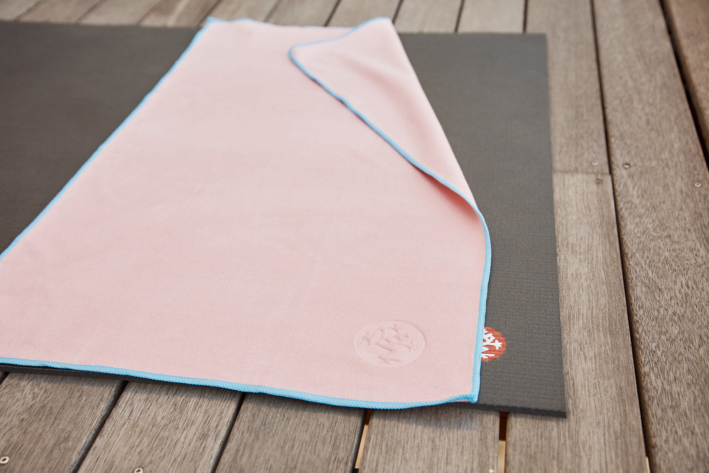 eQua Hand Towel in the colour Coral placed on a Black PROLite 5mm yoga mat - Manduka | Eco Yoga Store