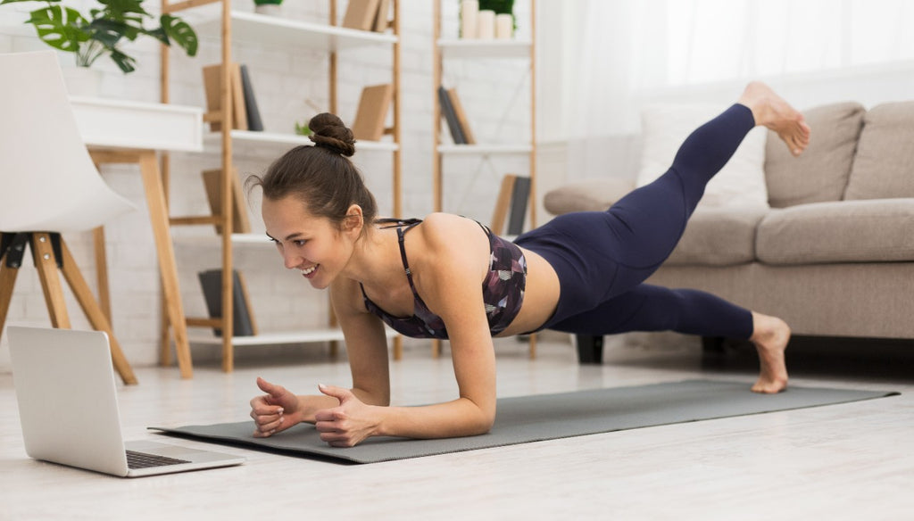 Yogi at home on her mat in front of a laptop | Eco Yoga Store