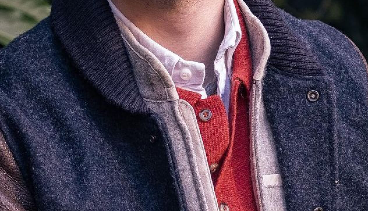 Person wearing layered jackets and a collared shirt.