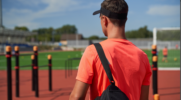 Man at track holding bag with track spikes