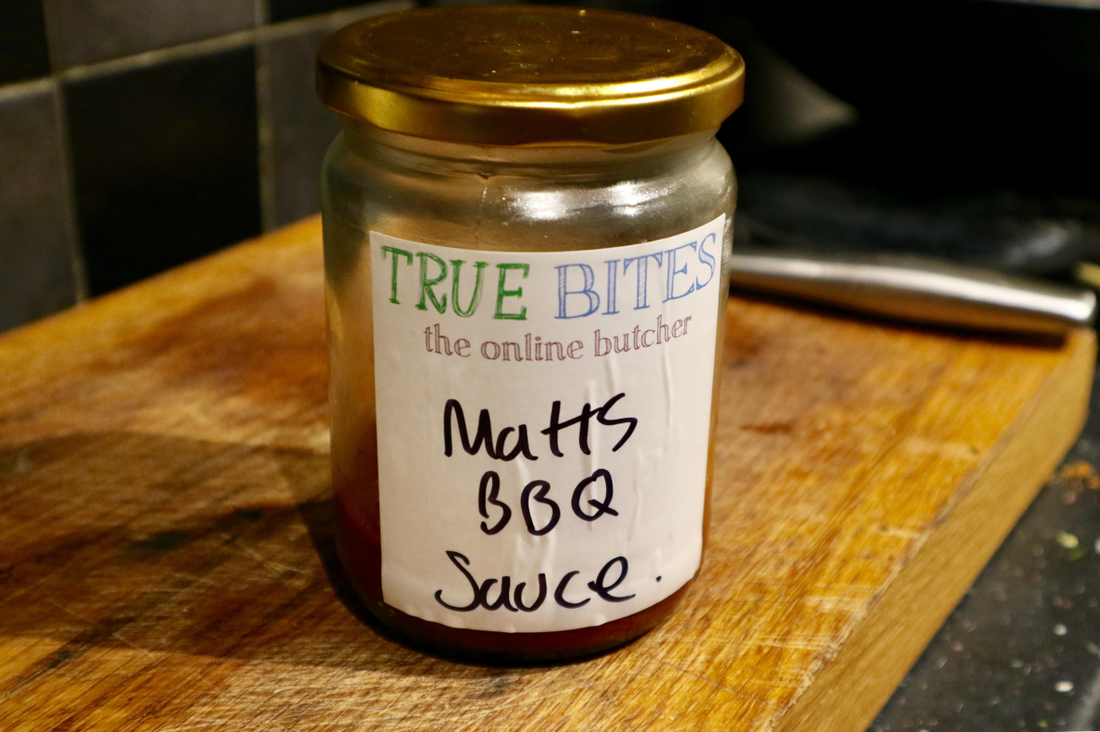 a glass jar containing homemade bbq sauce with a white label on it reading 'matts bbq sauce'