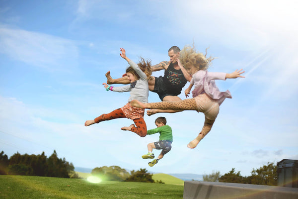 Three active kids jumping off a wall onto grass with their fitness focussed dad Adam - Mountain Buggy in association with Cadenshae Dad Blog