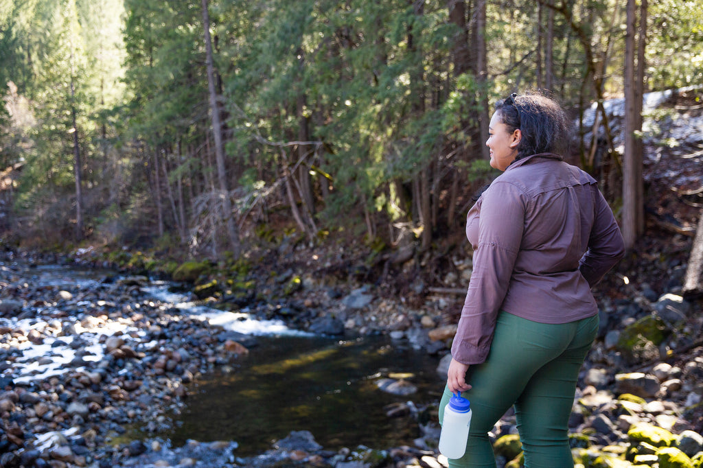 A woman stares at a beautiful river scene in her Ponderosa Pants. 