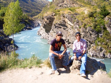 Tom and his friend in New Zealand 2005, sitting on rocks in front of a river