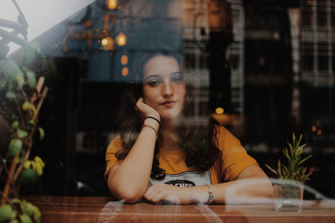 lady sitting and looking outside the window glass