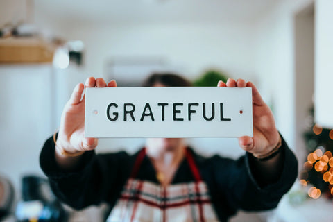 person holding white and black grateful print card