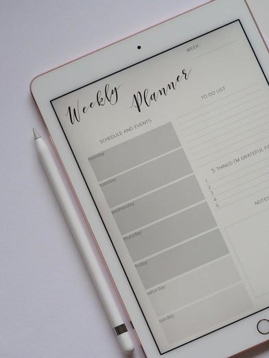 An iPad showing a digital weekly planner, next to an Apple Pencil