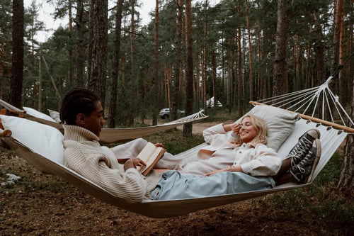 two people lying in a hammock in a forest