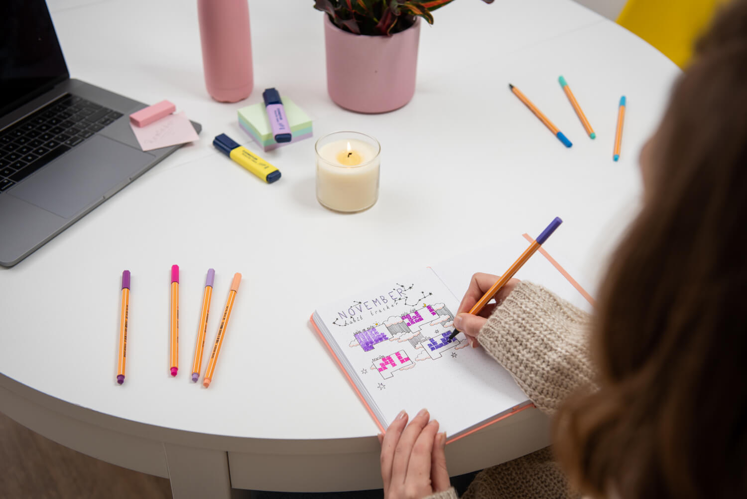 lady drawing in bullet journal on table