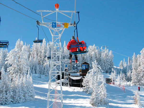 A person rides a ski lift over fresh snow.