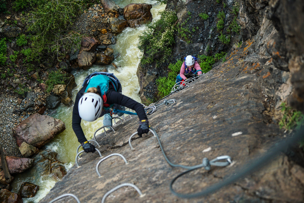 Climbers ascend the rock above a river in Ouray, Colorado's Via Ferrata.