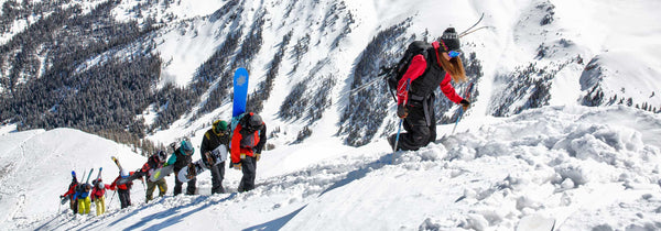 A group of skiers hike uphill.