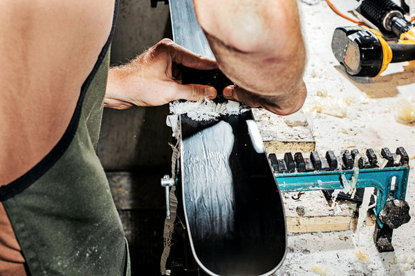 A person scrapes wax off of their skis.