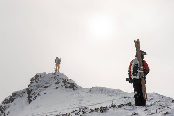 A skier stands at the summit of a mountain.
