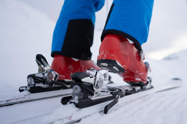 A person clicks into their bindings in some snow.