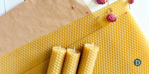 beeswax candles on a brown paper and white wood background