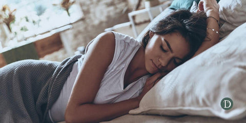 Peacefully sleeping woman in a white tshirt covered with soft grey blanket.