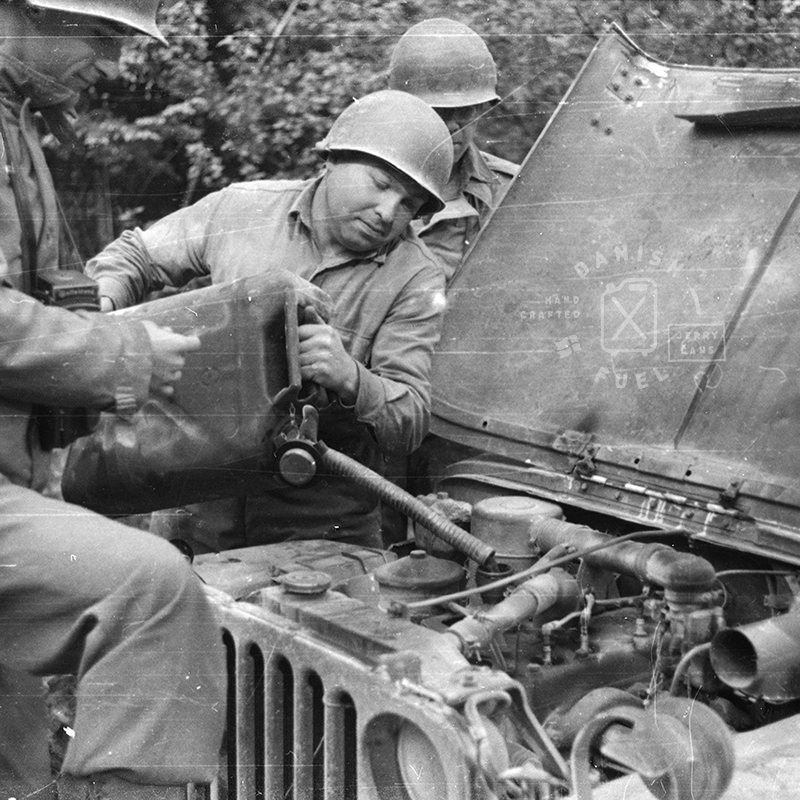 Soldiers fills up a Jeep with oil using a Jerrycan