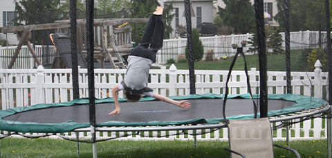 a boy is doing backflip on large trampoline