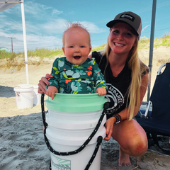 Woman wearing the Trucker Hat at the beach with a baby