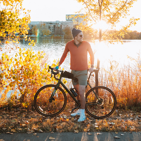Man wearing a beanie holding a bike in fall