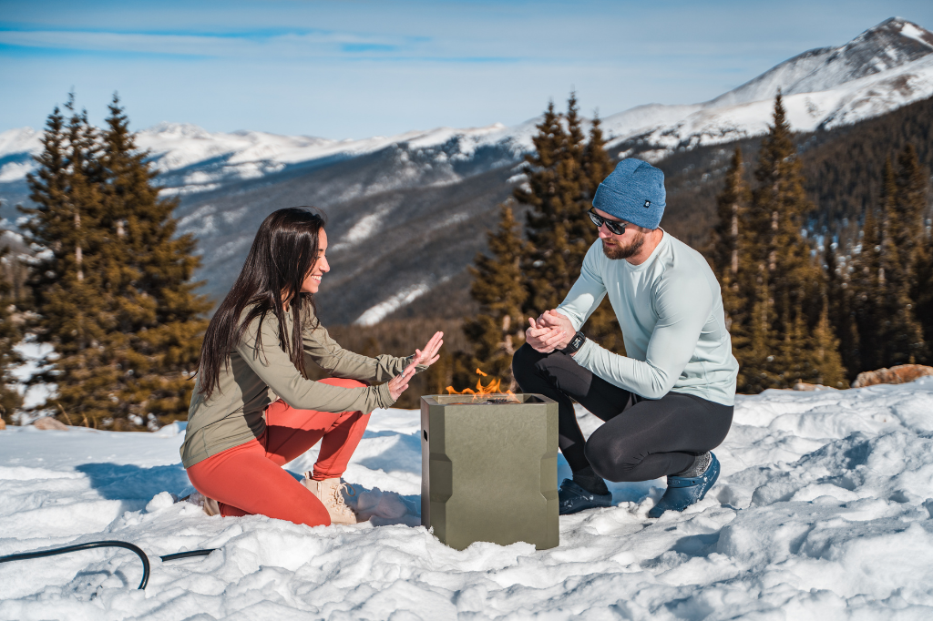 Couple-in-snow-warming-hands-over-a-fire