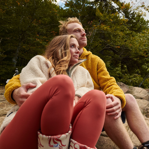 man and woman wearing sherpa fleece sitting on a rock