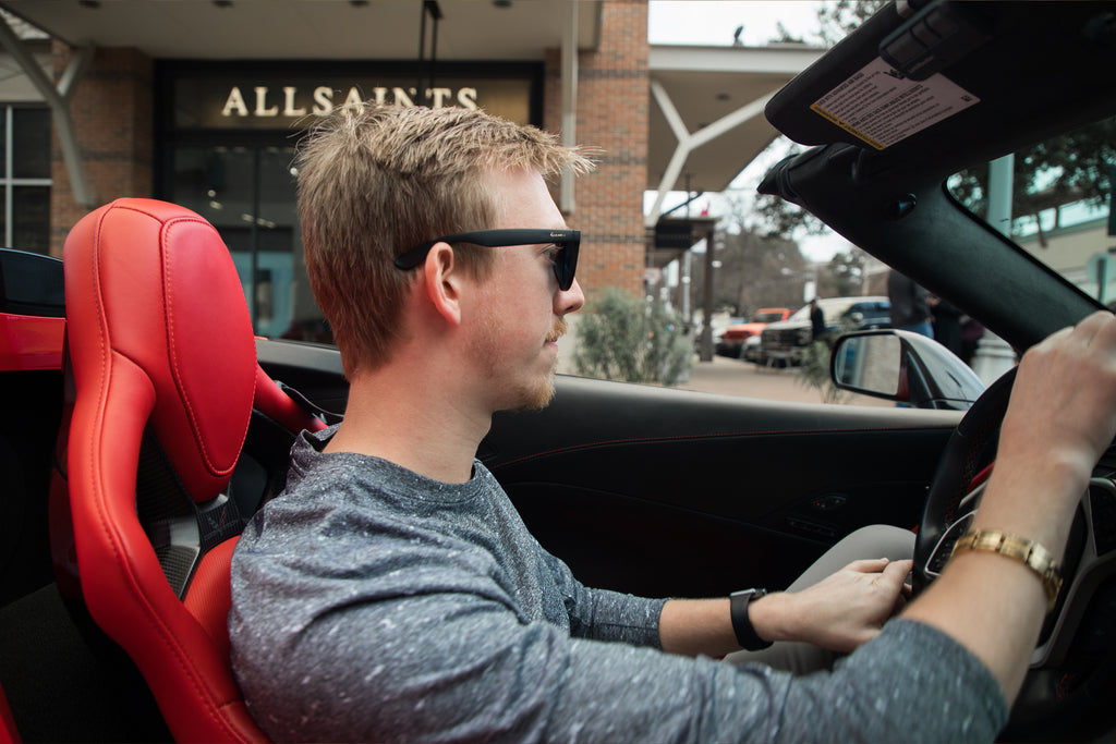 Man driving a car wearing black sunglasses