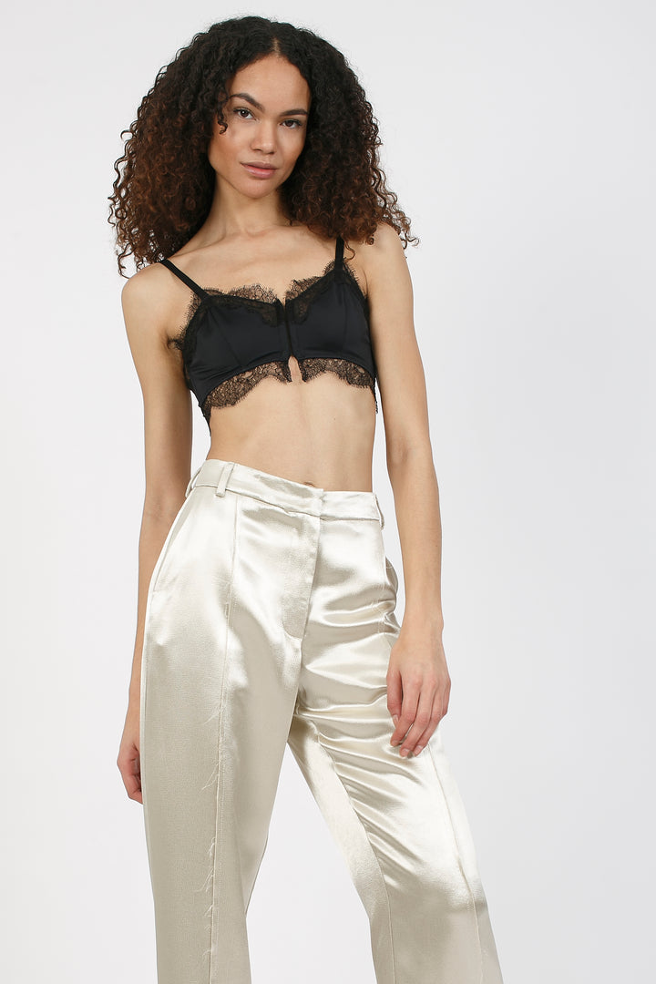 Model wears champagne silk trousers with black silk bralette designed by Ianua