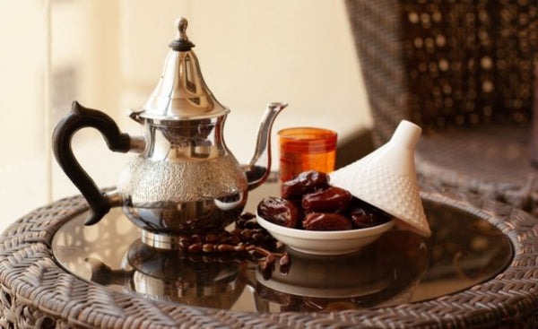 une théière arabe sur une table à côté d'un bol avec des dattes