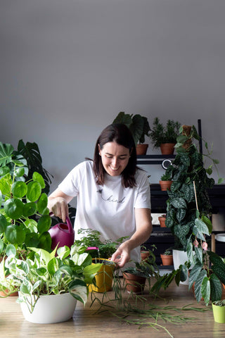 Catherine O'Sullivan  surrounded by plants watering another plant