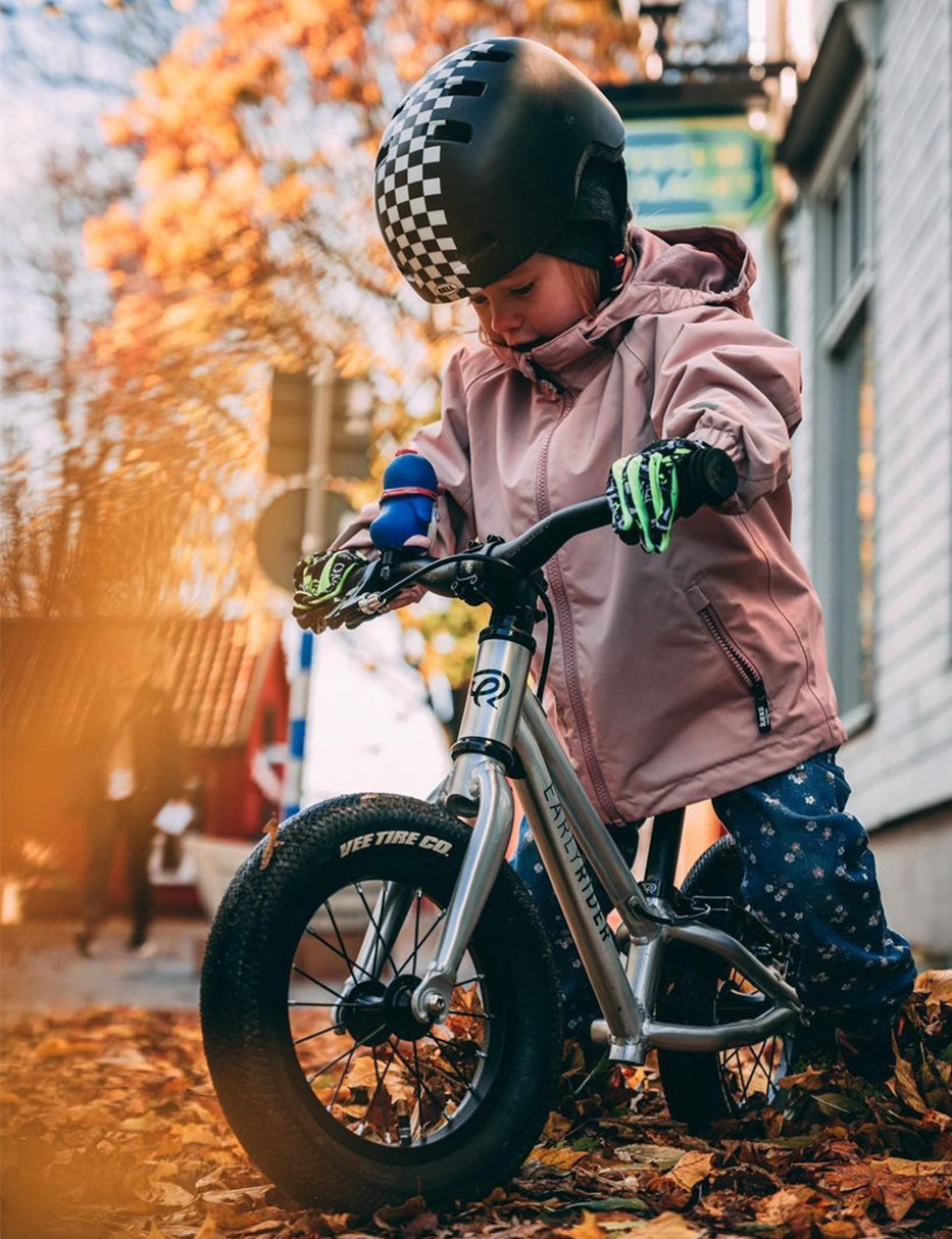 Girl riding her balance bike through autumn leaves