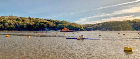 River fowey Rnli lifeboat heading to the English Channel past canoes, kayaks and gig rowers