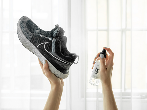 hands spraying a pair of nike sneakers after a workout