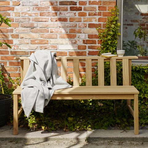 A brown bench rests against the wall of a house