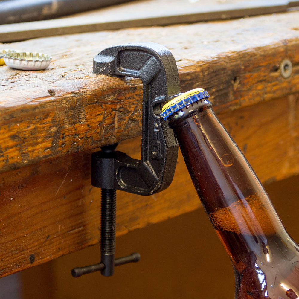 A bottle opener clamped to a workbench